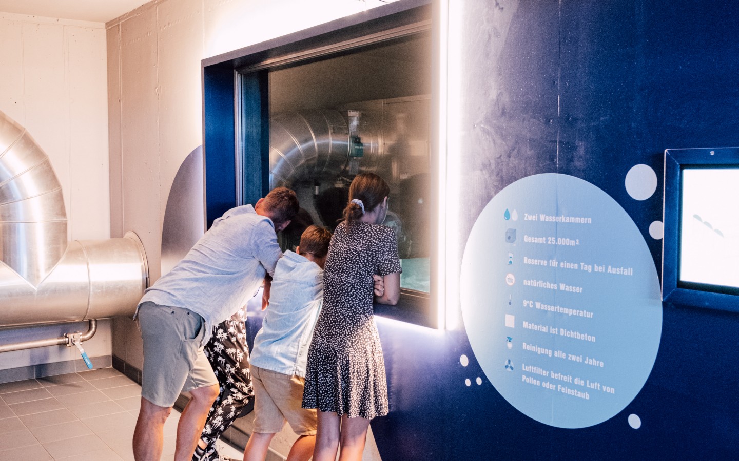 Familie mit Kindern sieht sich ein Ausstellungstück im Wassermuseum WasserSpiegel in Salzburg an