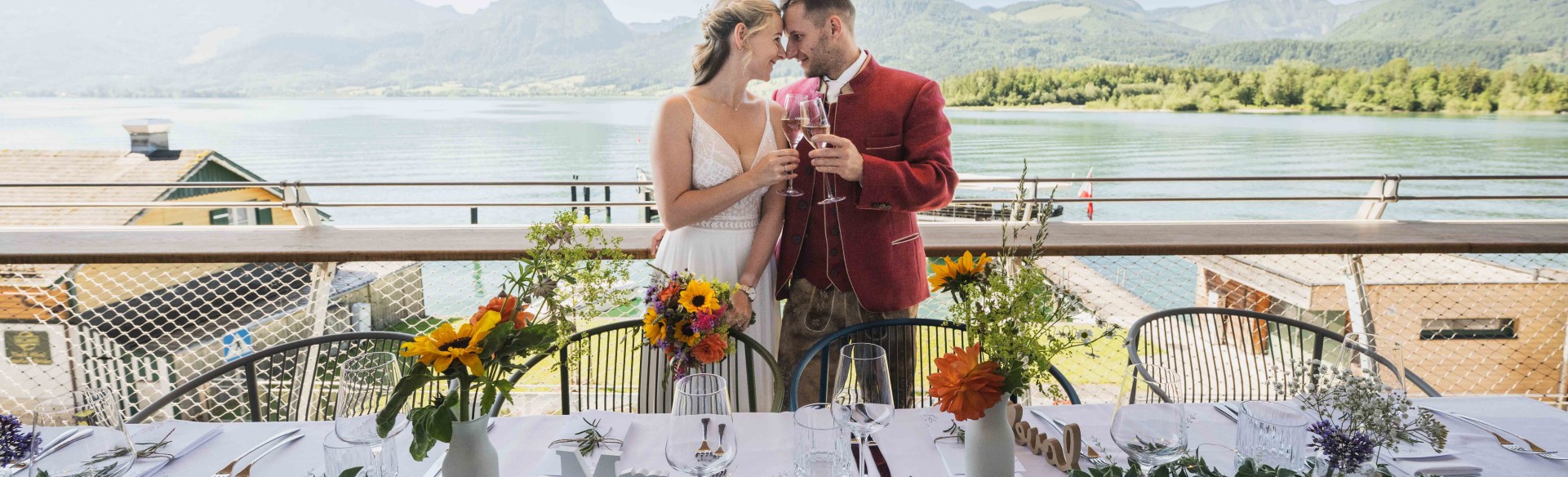 Das Hochzeitspaar auf der Terrasse und am gedeckten Tisch des Restaurants des ErlebnisQuartier, der Talstation der SchafbergBahn in St. Wolfgang am Wolfgangsee.