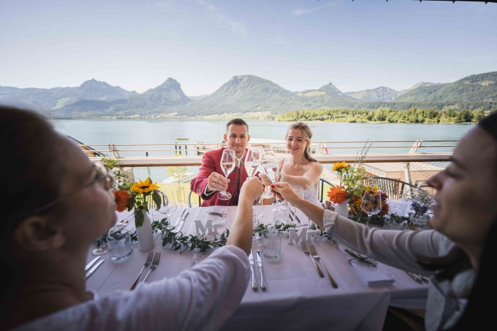 Das Hochzeitspaar auf der Terrasse und am gedeckten Tisch des Restaurants des ErlebnisQuartier, der Talstation der SchafbergBahn in St. Wolfgang am Wolfgangsee.